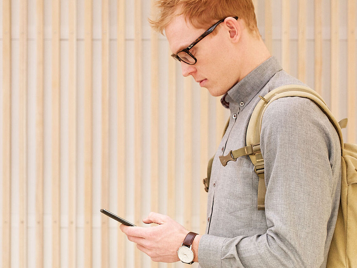 Cand.it.-studerende Niels Elmegaard Bæk med smartphone og rygsæk